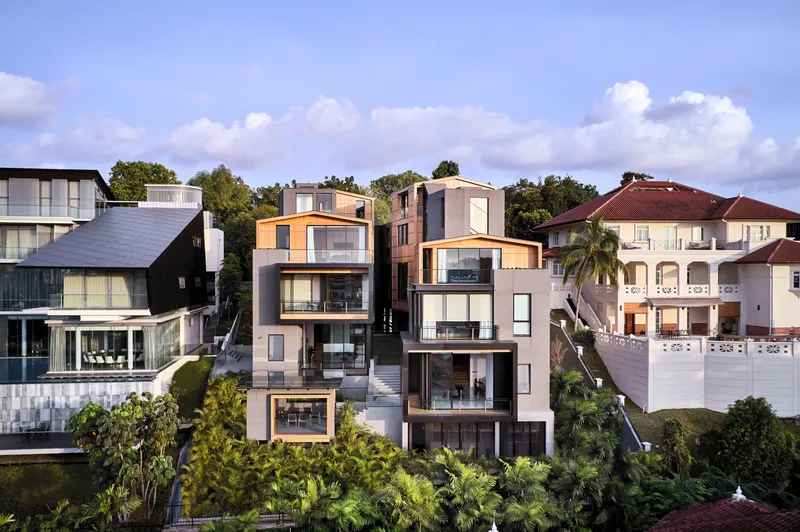 Modern multi-level home with stacked geometric volumes beside a colonial house