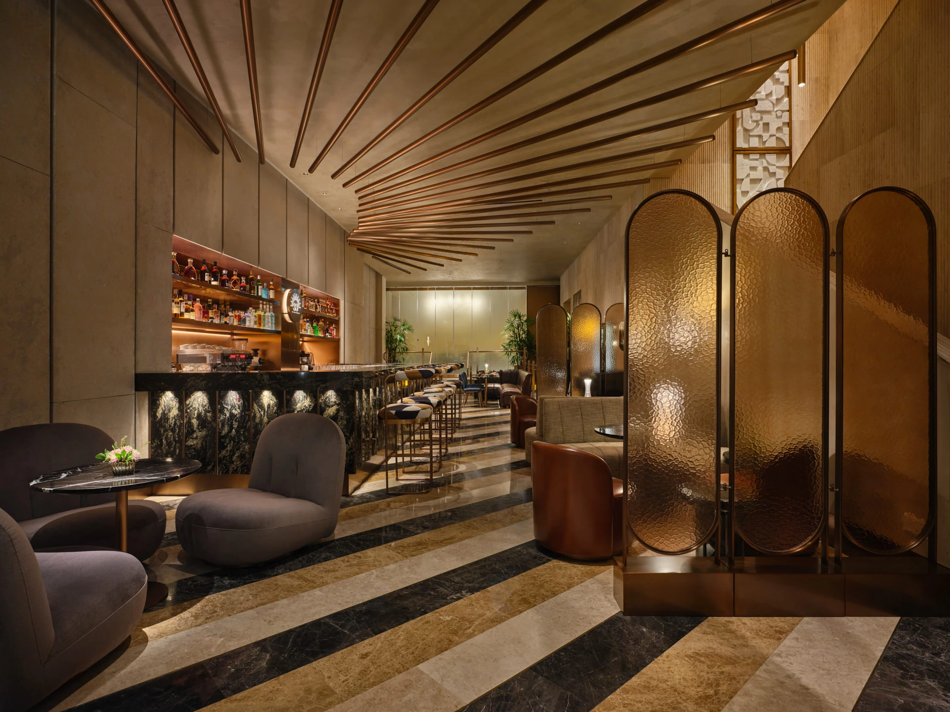 Lounge with velvet chairs, hammered copper screens and striped marble floor