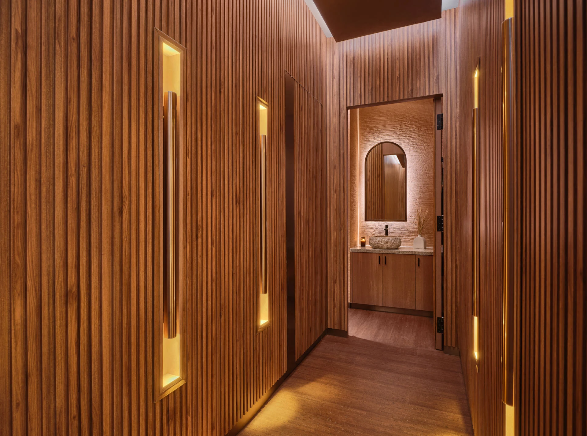 Spa corridor with teak slats, amber wall niches and stone basin