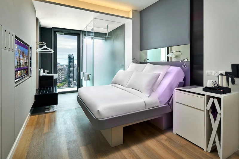 Full cabin view with queen bed, vanity, shower and Singapore skyline window