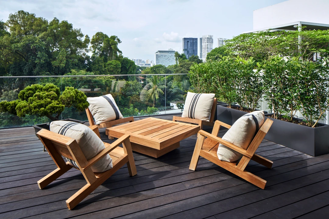 Balcony seating area with wooden furniture and lush greenery