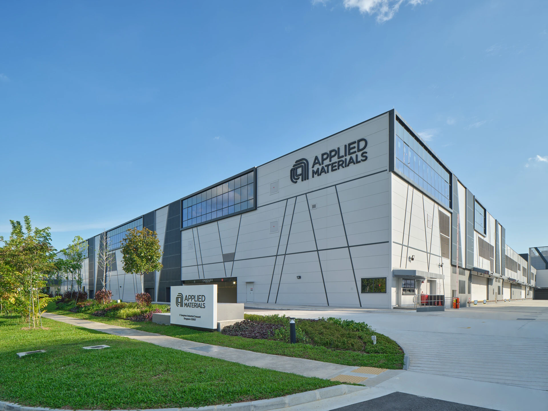 Approach view with branded signage, angular facade and tropical landscaping