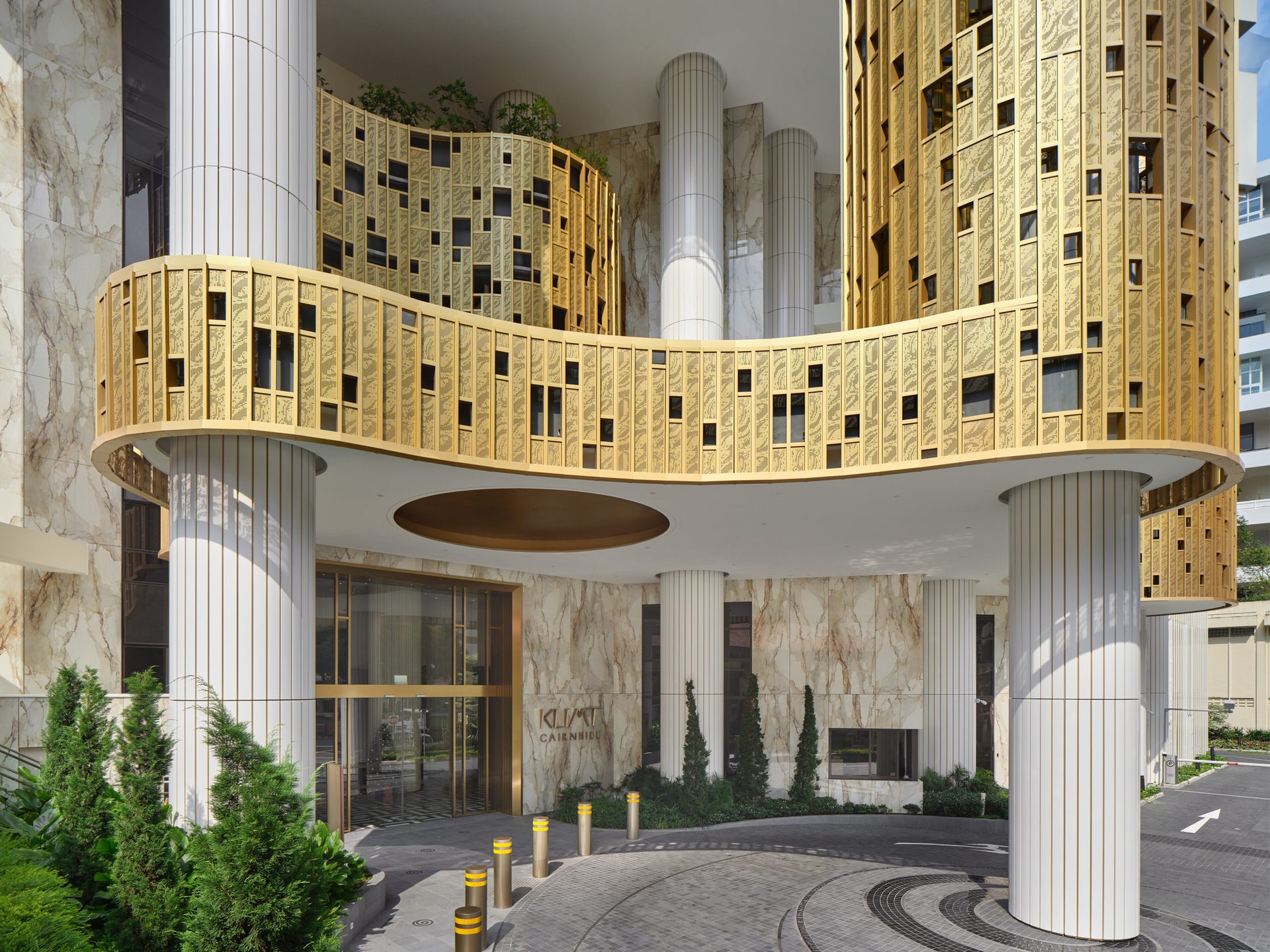 Klimt Cairnhill porte-cochère entrance with Atlas Concorde gold mosaic tile facade, marble-effect porcelain walls, and white fluted columns