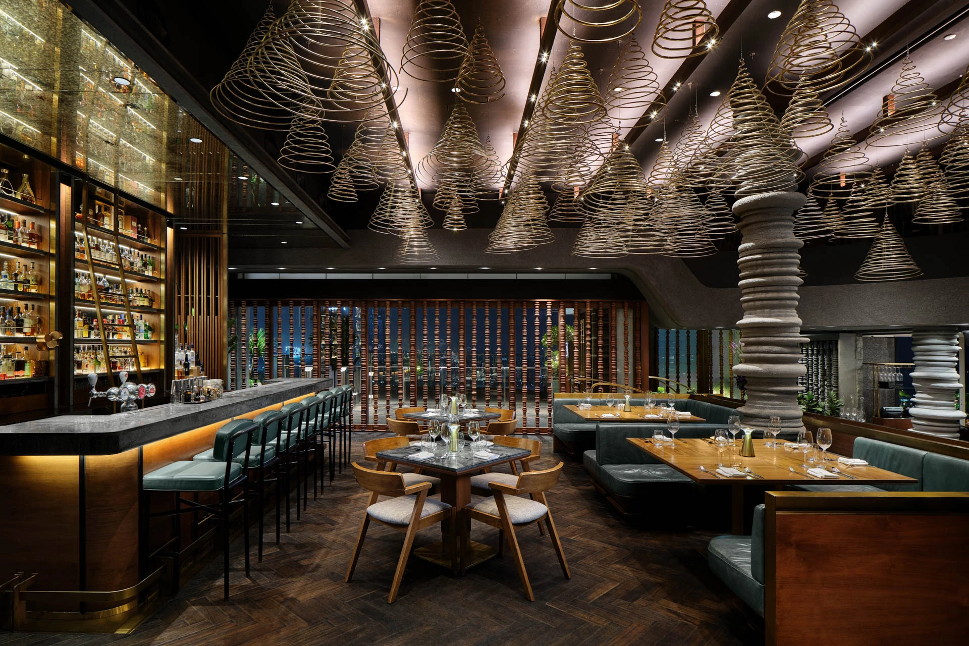 Upper dining level with spiral cone ceiling pendants, herringbone timber floor, teal banquettes, and illuminated bar