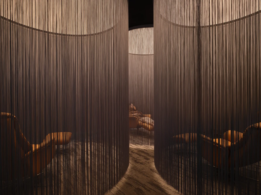 Wellness retreat room with string curtain partitions and timber loungers