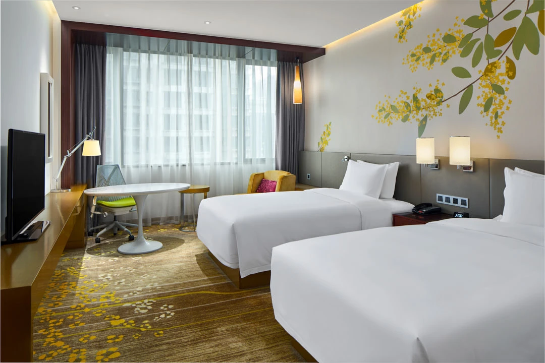 Twin room with floral headboard, yellow chair and gold carpet