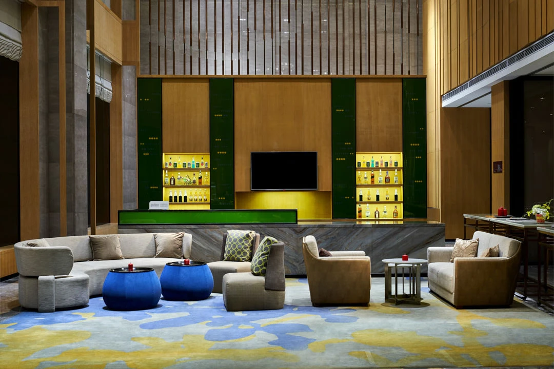 Double-height lobby bar with marble counter and backlit liquor display