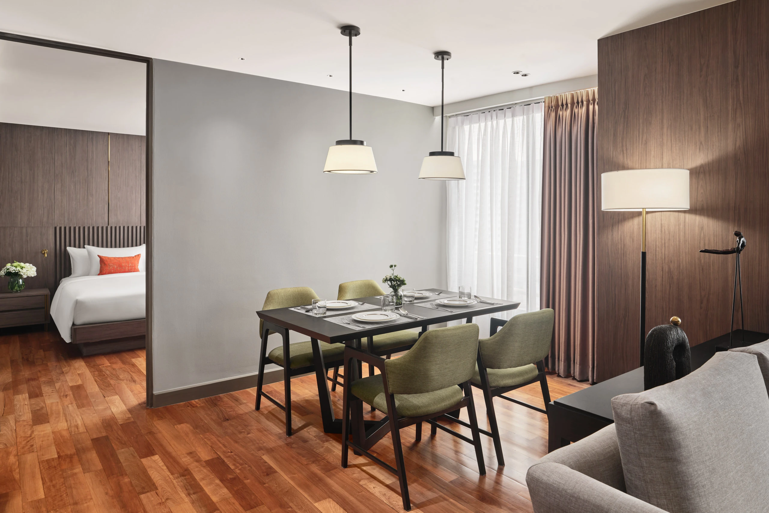 Suite dining area with olive chairs, twin pendants and bedroom beyond