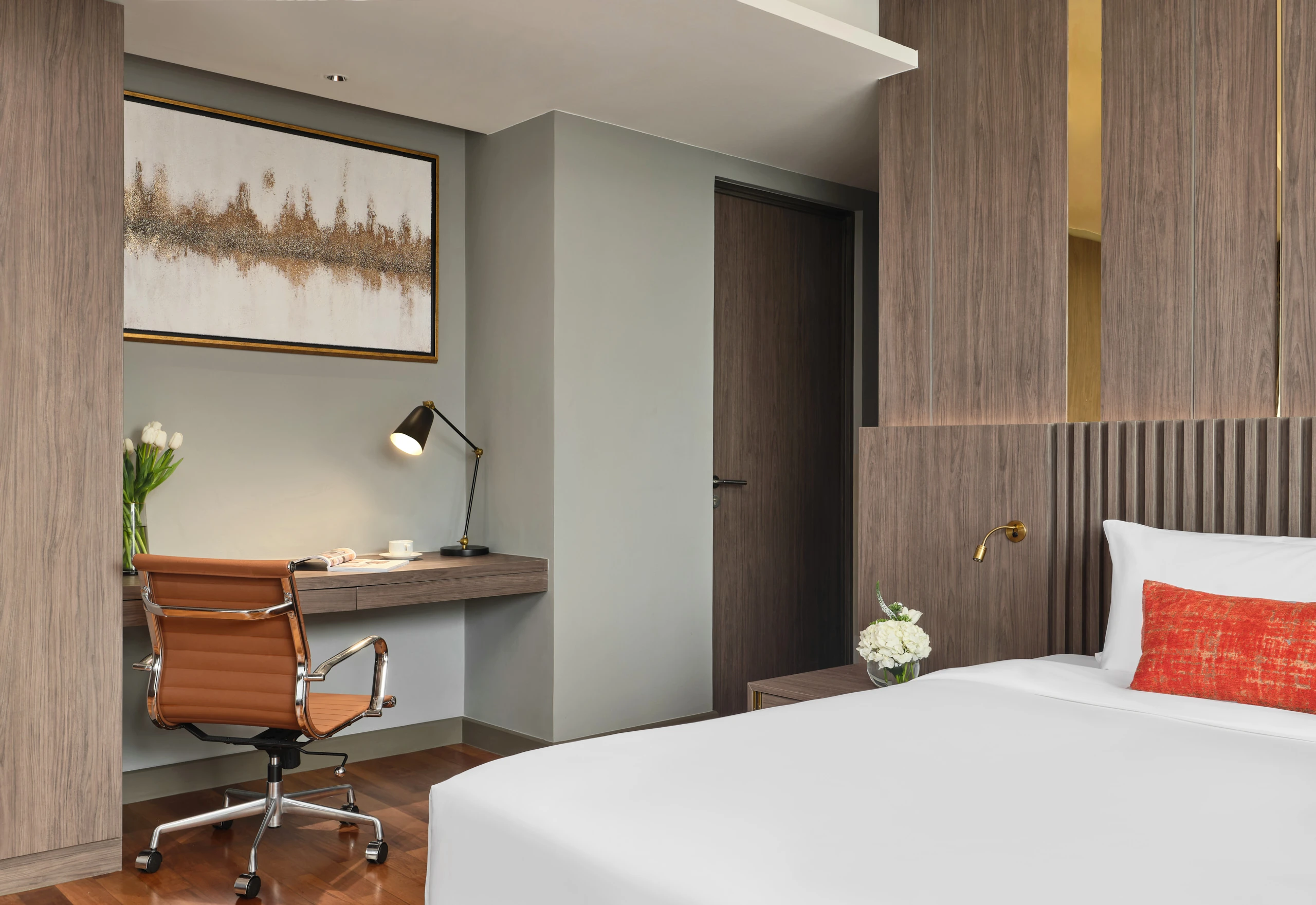 Bedroom desk niche in sage wall with cognac leather chair and artwork