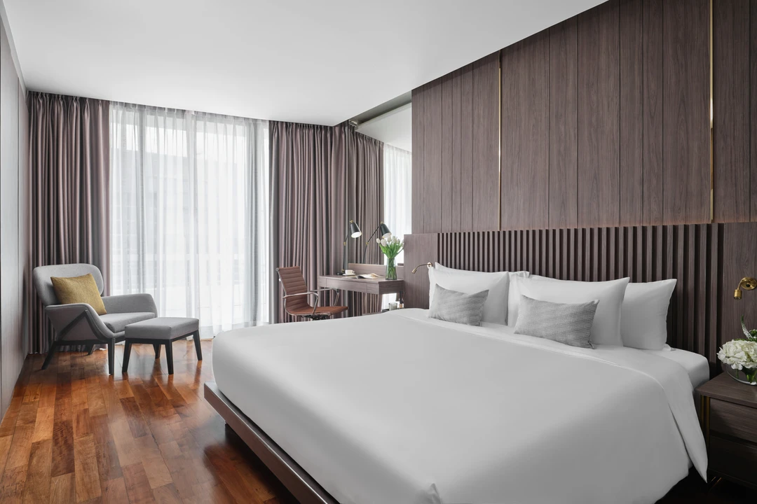 Suite king bedroom with walnut slatted headboard and grey lounge chair