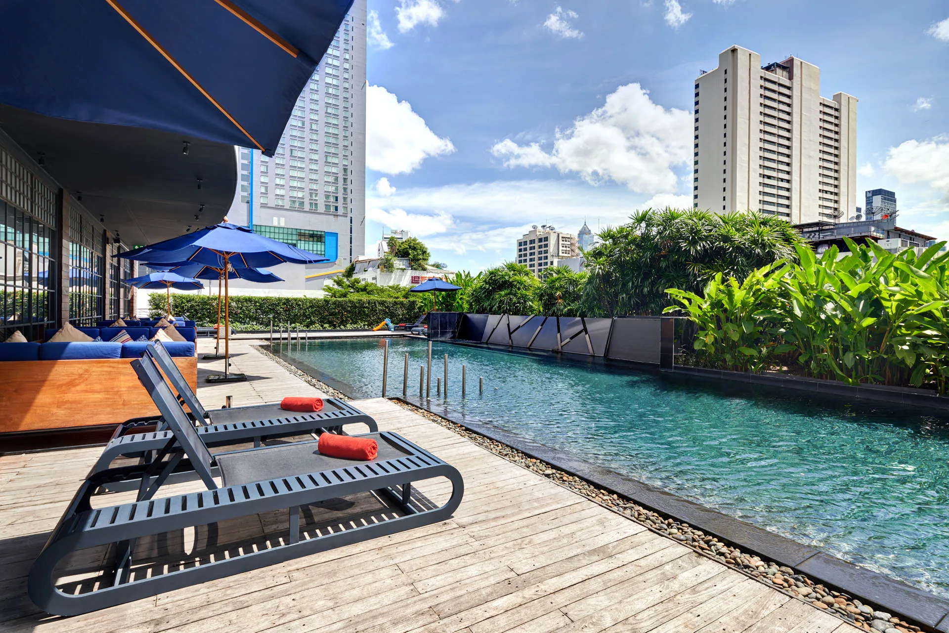 Rooftop infinity pool with sun loungers and Bangkok city skyline at Fraser Suites Sukhumvit