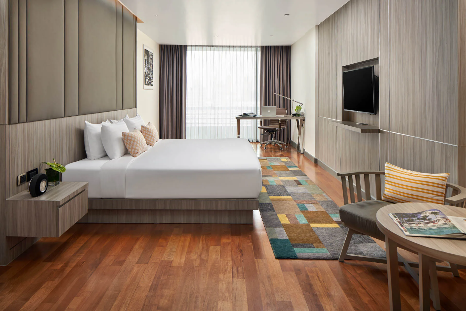 Studio executive king room with timber floors, padded headboard, colourful runner rug and work desk
