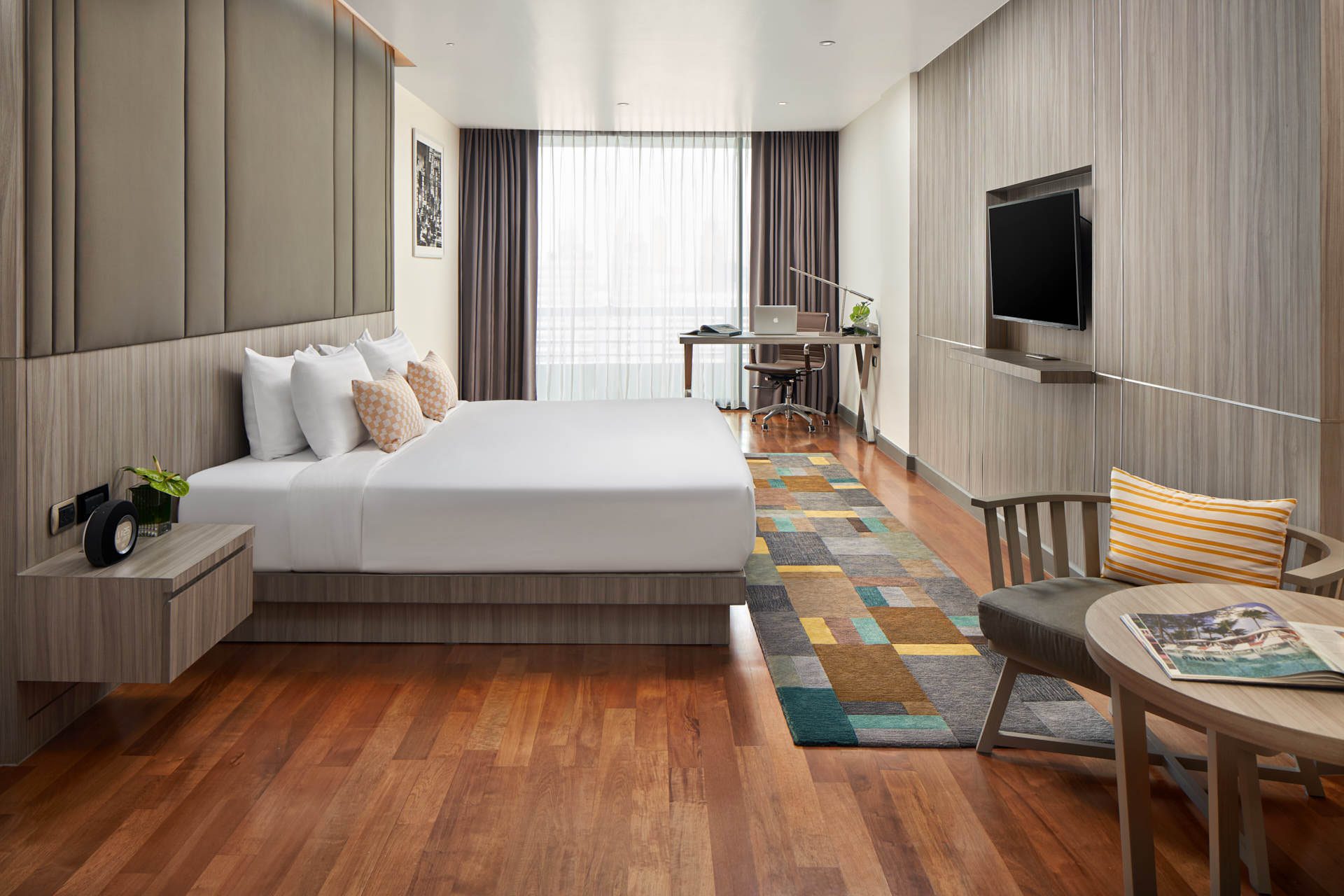 Studio executive king room with timber floors, padded headboard, colourful runner rug and work desk