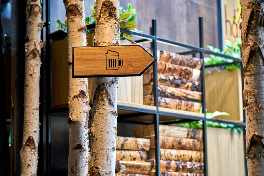 Restaurant photography detail of a rustic wooden sign and decorative stacked logs, central to Hans Im Gluck’s unique WOLF-designed interior.