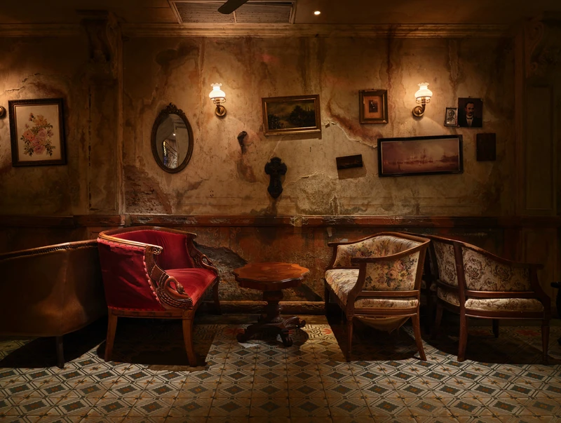 Intimate corner with vintage armchairs, oval mirror and distressed walls — Havana Social Bangkok interior photography