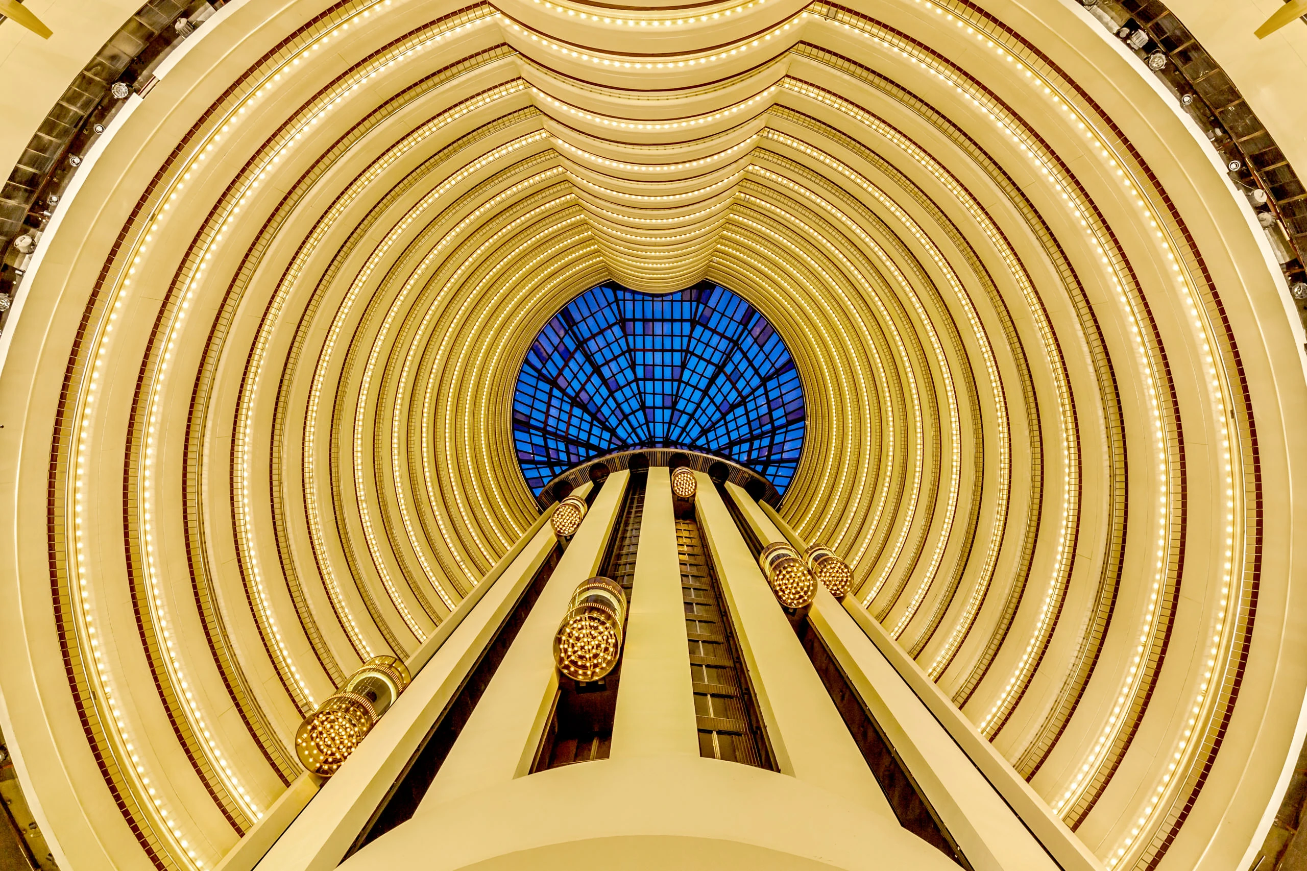 Grand atrium with golden balcony tiers, glass elevators and skylight dome