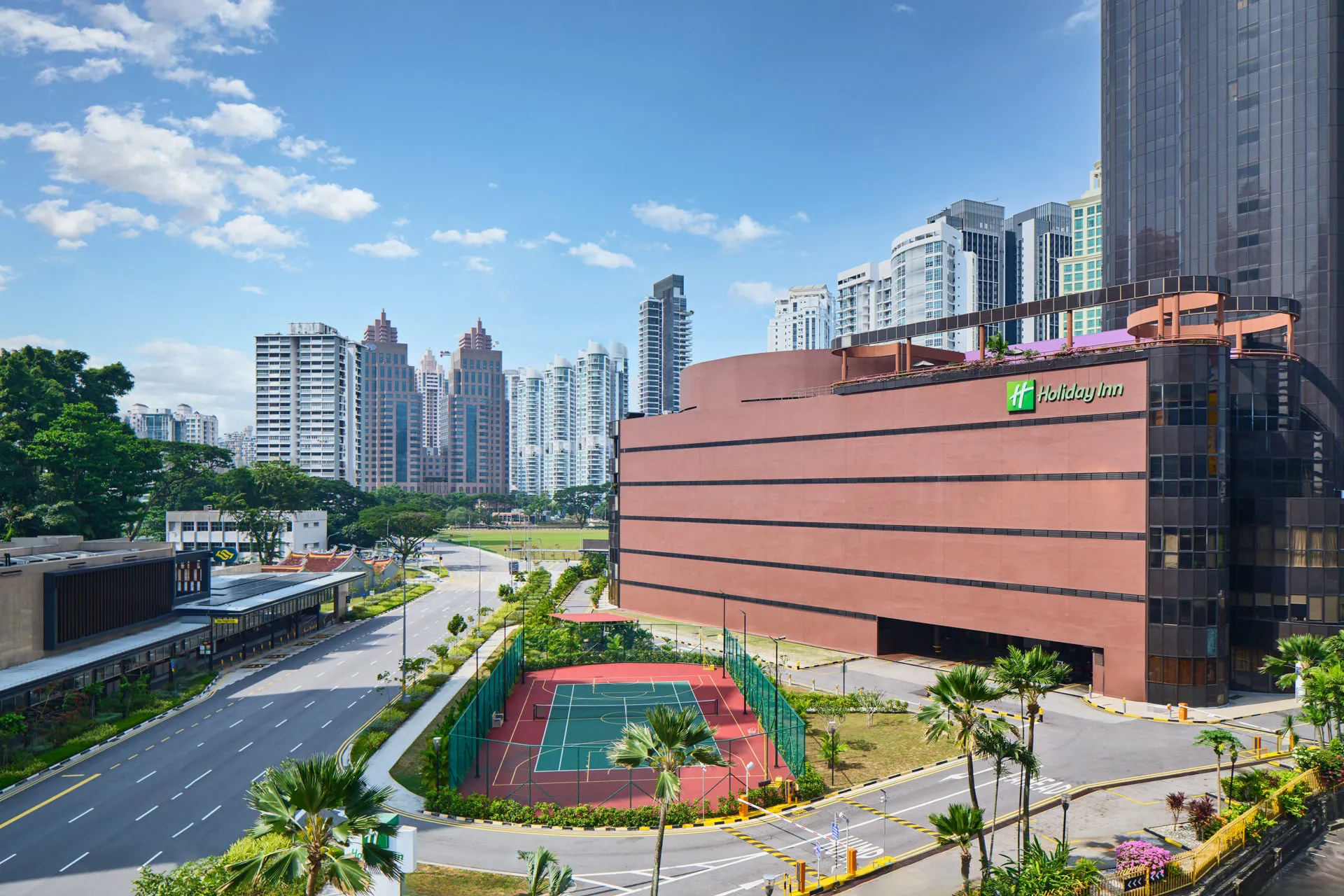 Aerial view of hotel complex with rooftop tennis court and city skyline — Holiday Inn Atrium Singapore architectural photography