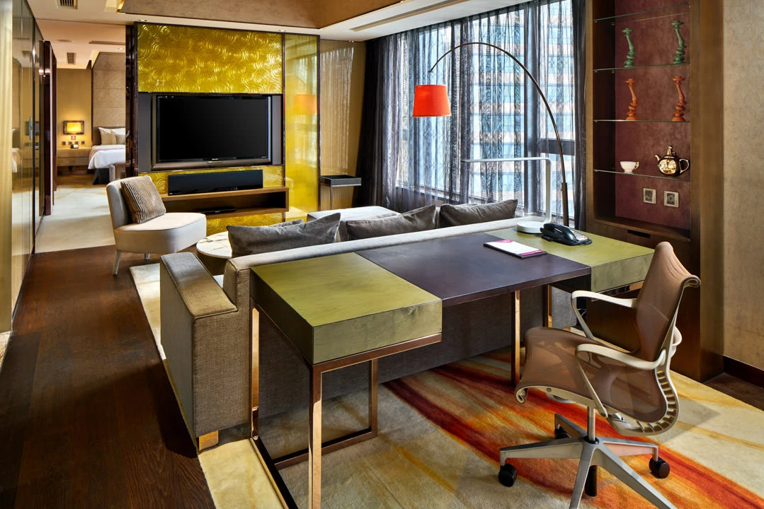 Suite living room with red arc lamp, gold accent wall and city views — Crowne Plaza Hong Kong interior photography