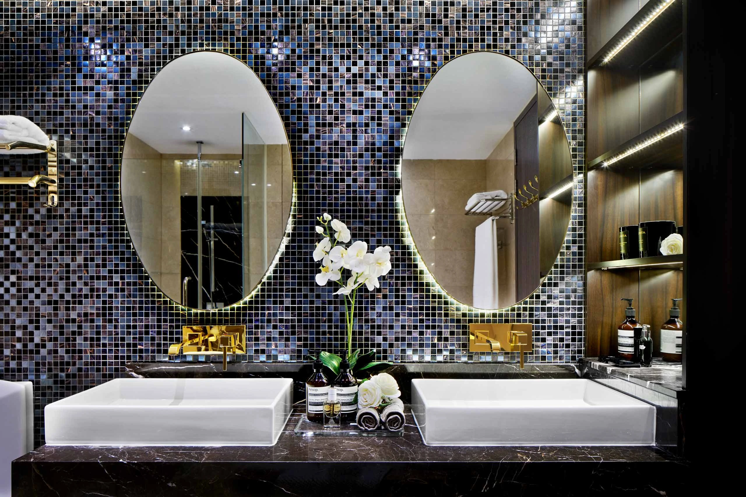Luxury master bathroom with twin sinks, mirrors, and mosaic wall