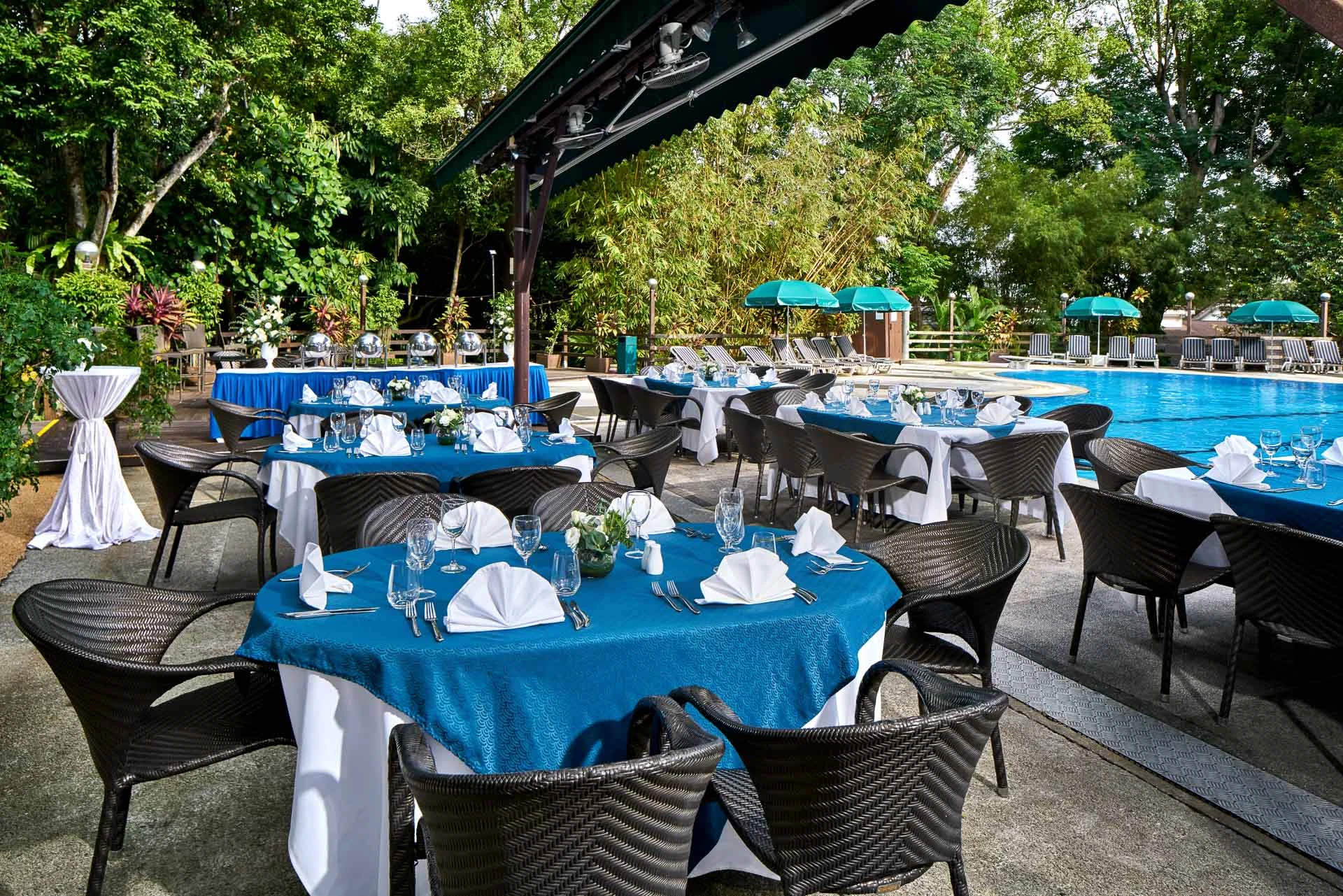 Poolside dining with teal linens and green umbrellas
