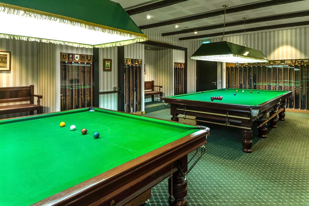 Billiards room with snooker tables, green shaded lamps and trophy plaques