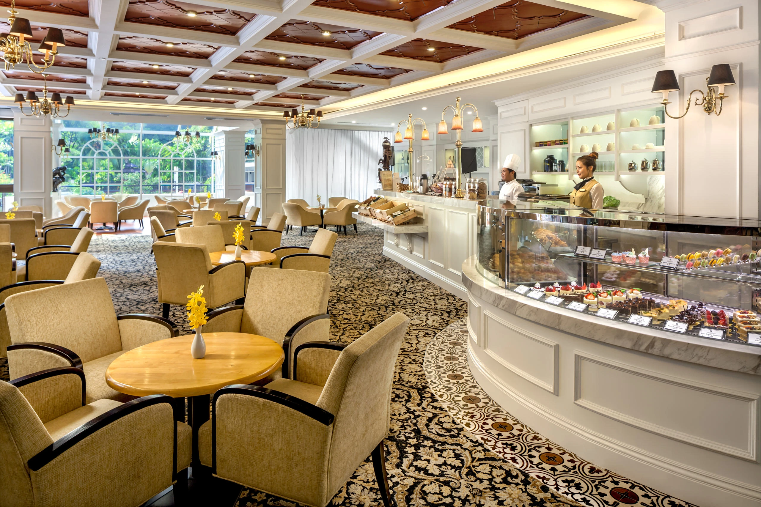 Tea room with marble pastry counter, brass chandeliers and floral carpet