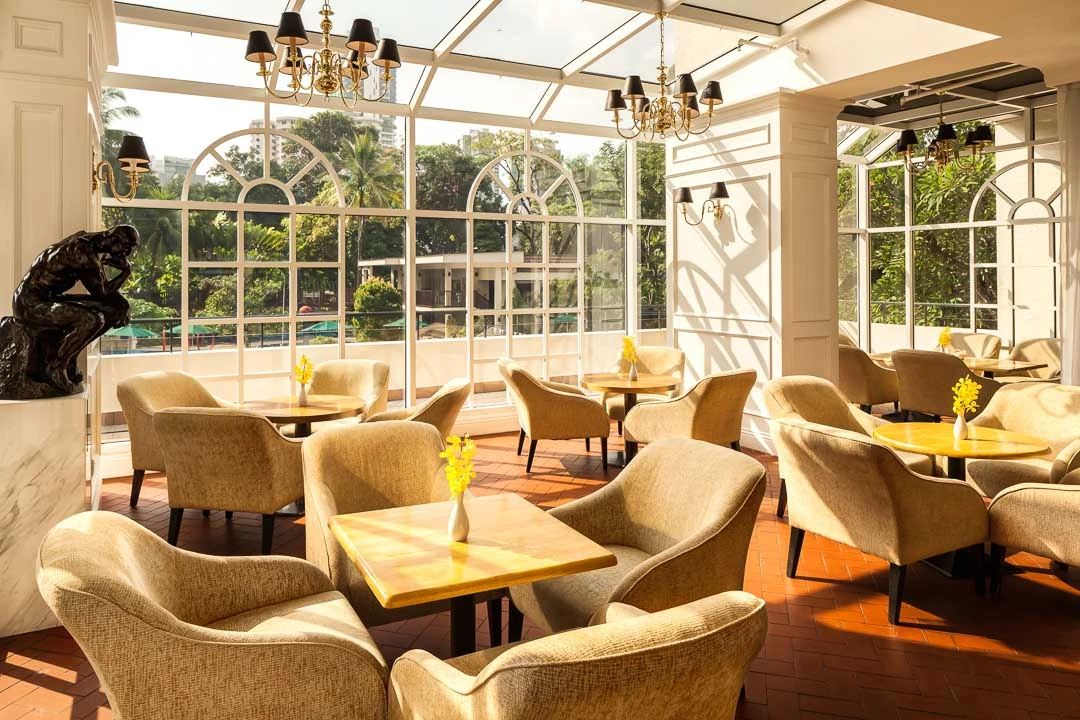 Conservatory lounge with arched glass windows and tropical garden views