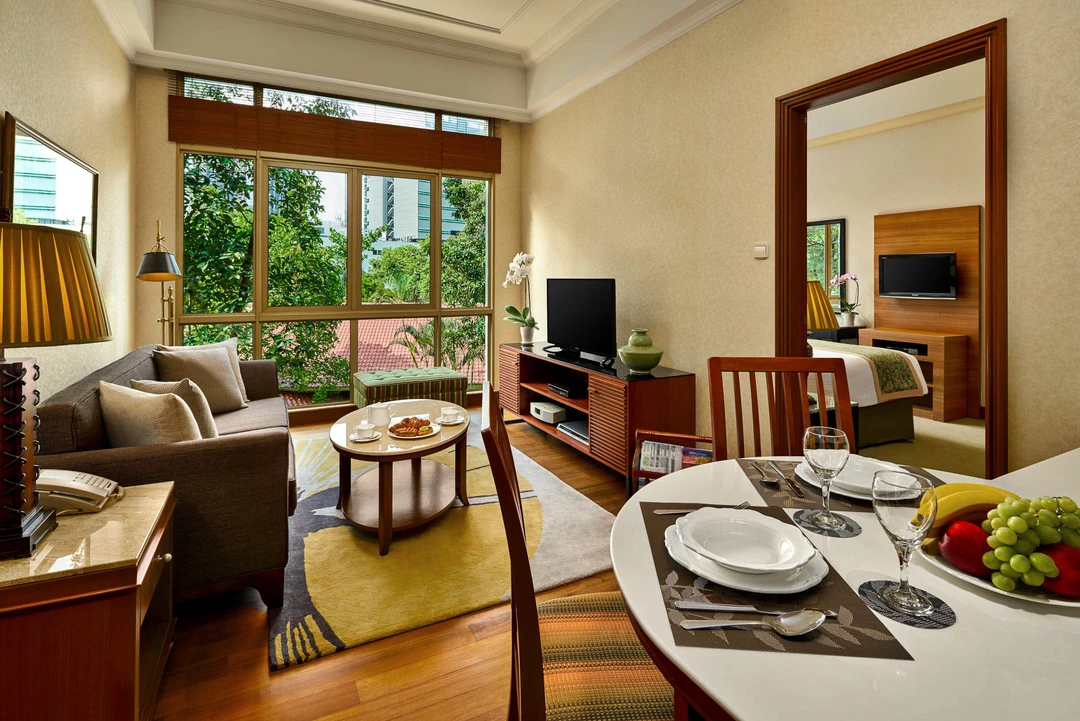 Compact living-dining with grey sofa, round table and green garden views - Treetops Singapore hospitality photography
