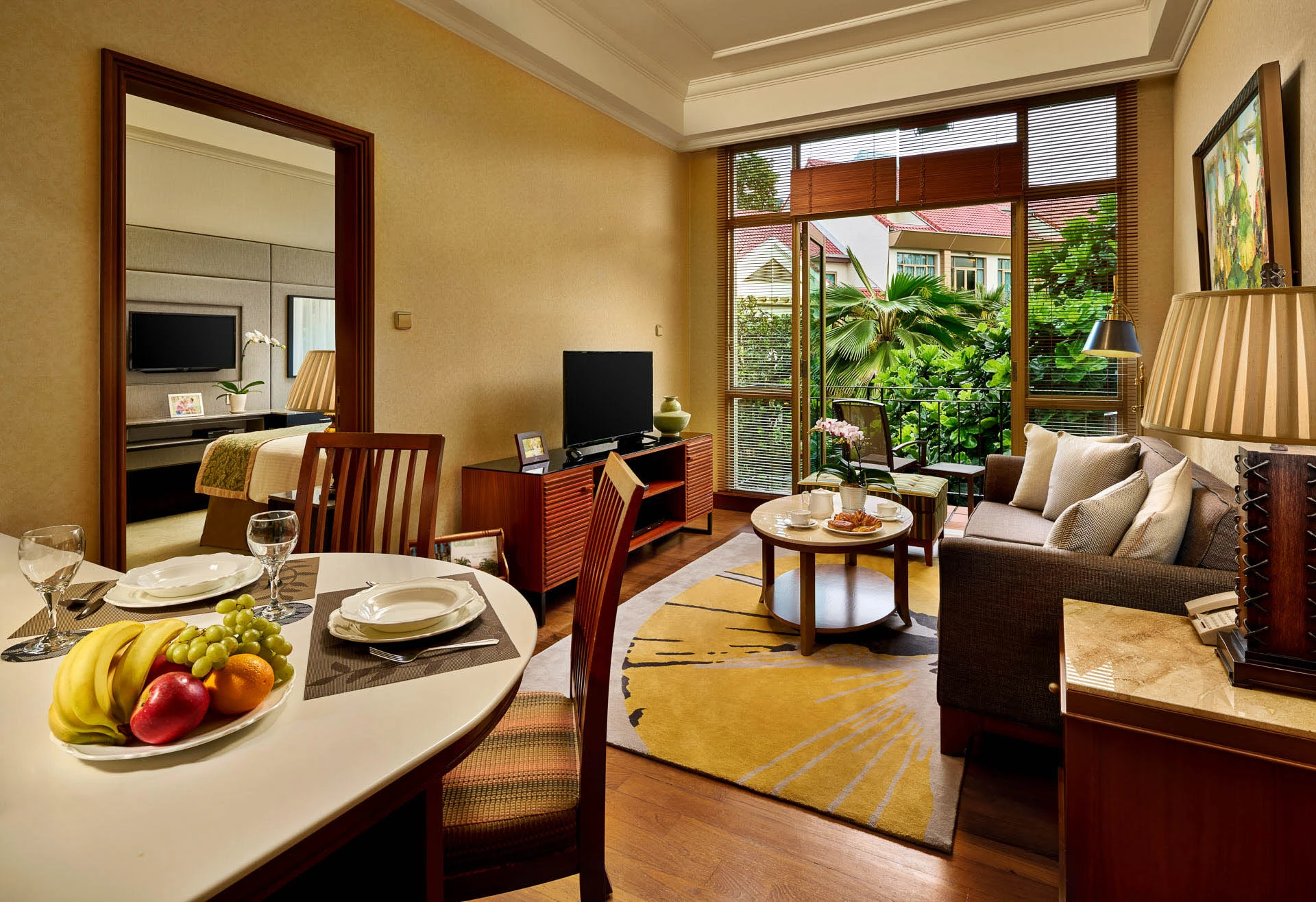 Living room with grey sofa, gold-black rug and tropical palm views - Treetops Singapore interior photography