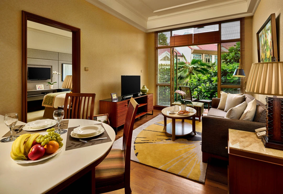 Living room with grey sofa, gold-black rug and tropical palm views - Treetops Singapore interior photography