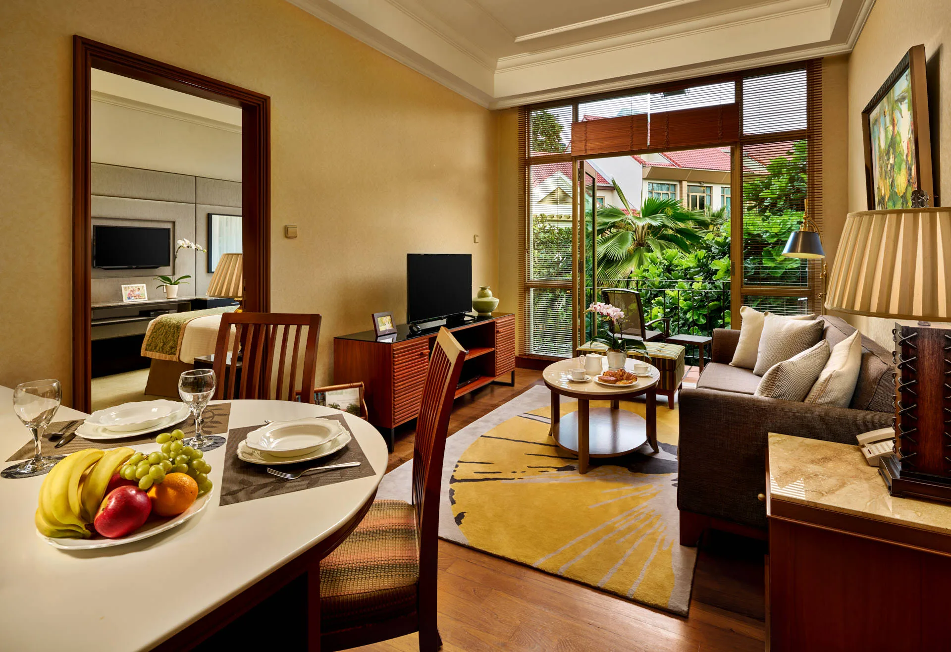 One-bedroom suite living room with grey sofa and garden view through venetian blinds - Treetops Singapore interior photography
