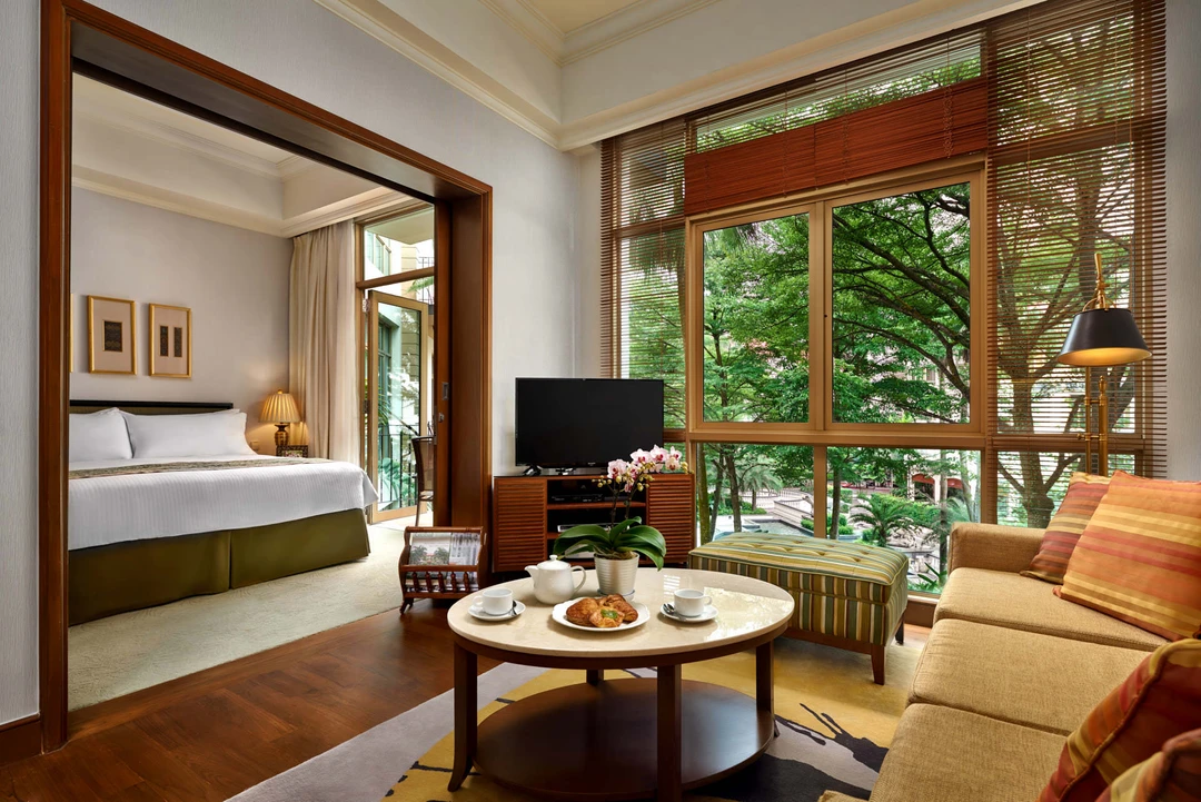 Suite living area with cream sofa, tea setting and tropical treetop views - Treetops Singapore hospitality photography