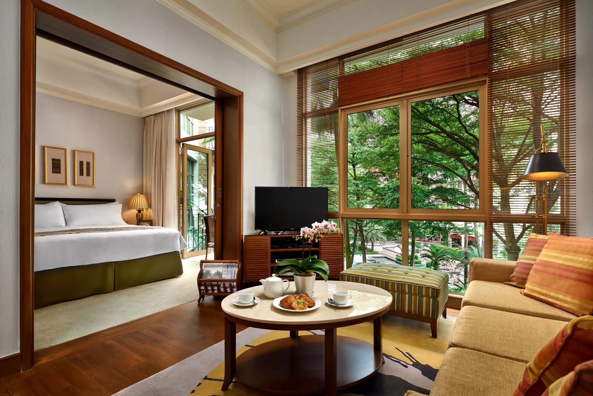 Suite living area with cream sofa, tea setting and tropical treetop views - Treetops Singapore hospitality photography