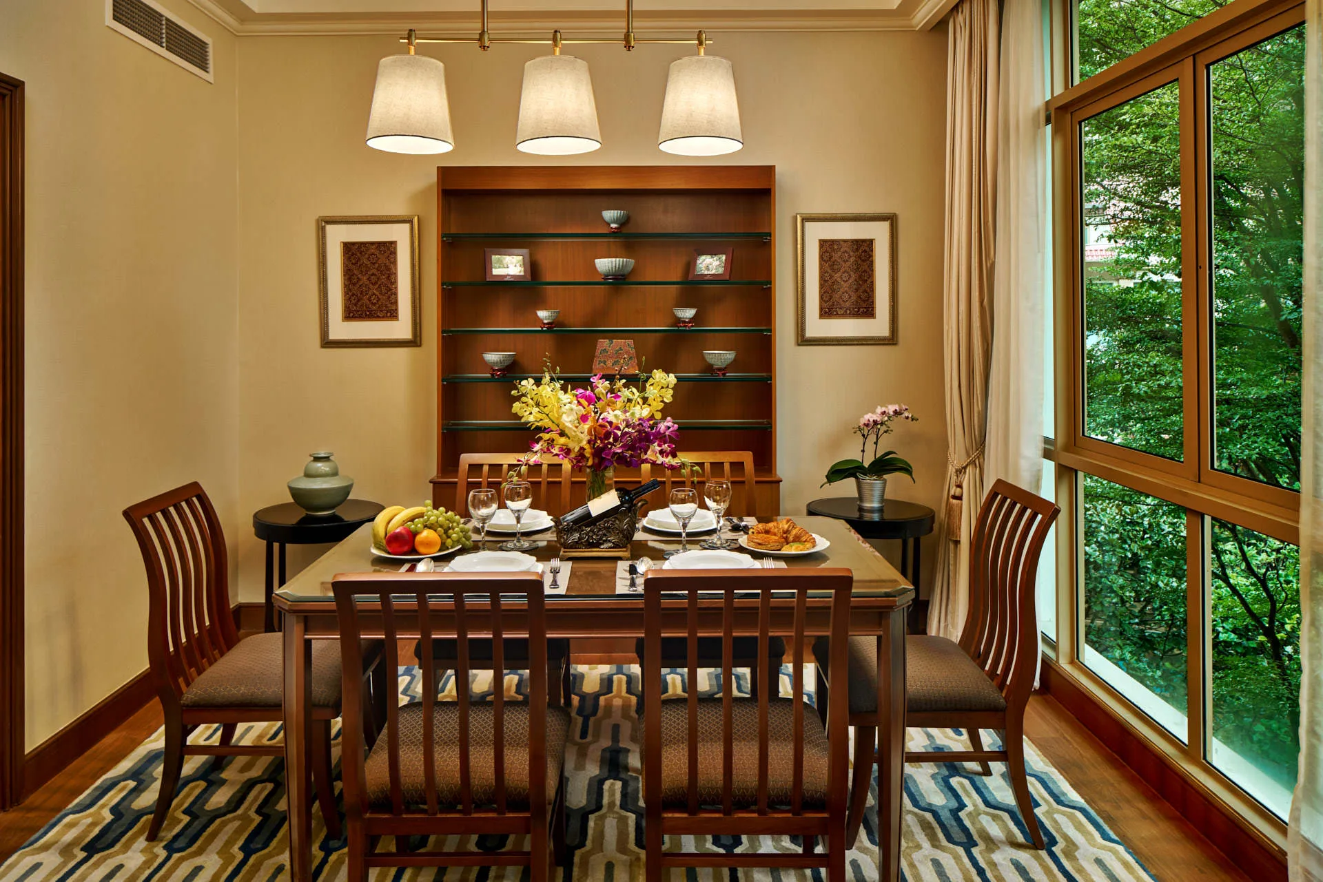 Dining table with brass pendant light and garden view display shelf - Treetops Singapore hospitality photography