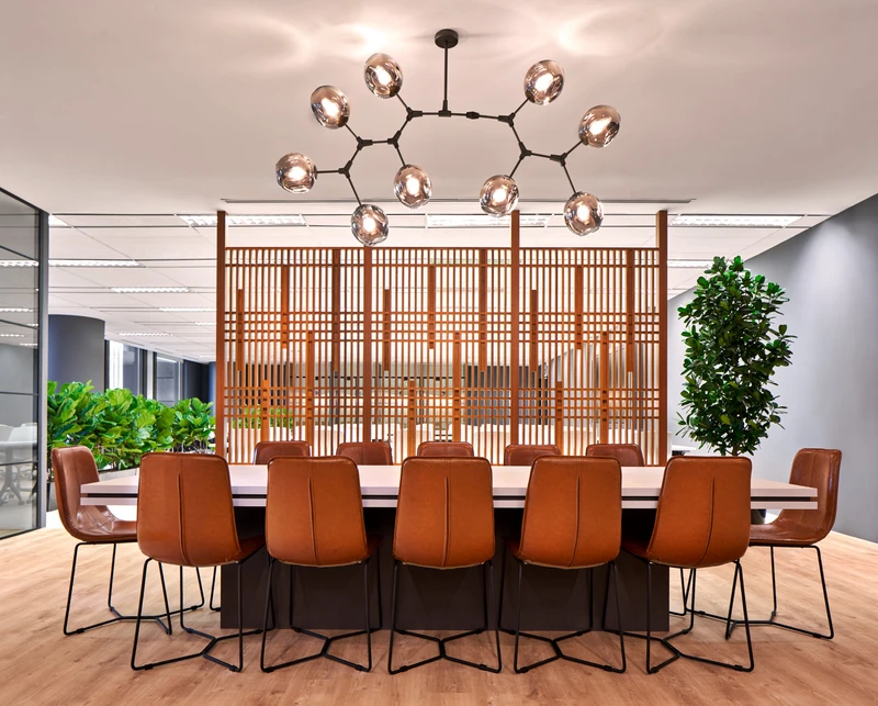 Large communal table with tan leather chairs, globe chandelier and wooden screen