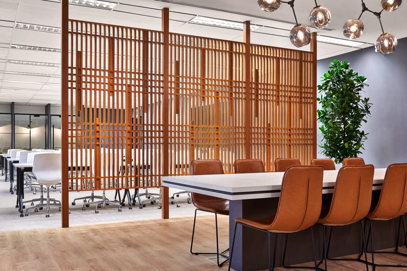 Long table with tan leather chairs behind a wooden slat screen divider