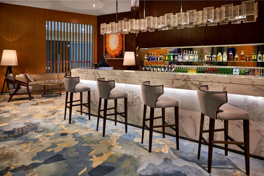 Hotel bar with marble counter, crystal chandelier and backlit spirits