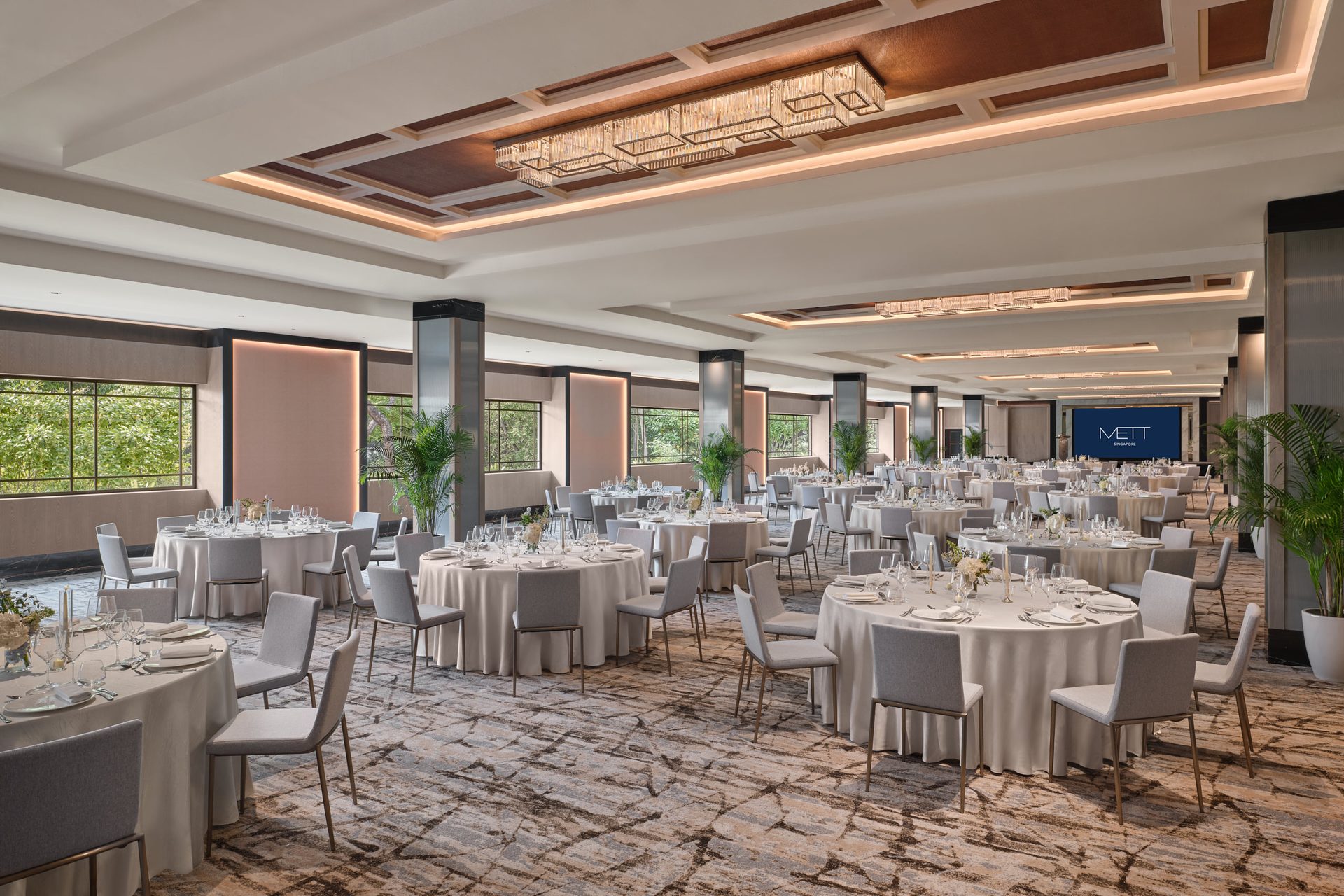 METT Singapore Grand Ballroom cluster setup with round banquet tables, stage screen, chandeliers, and heritage hotel function room interiors