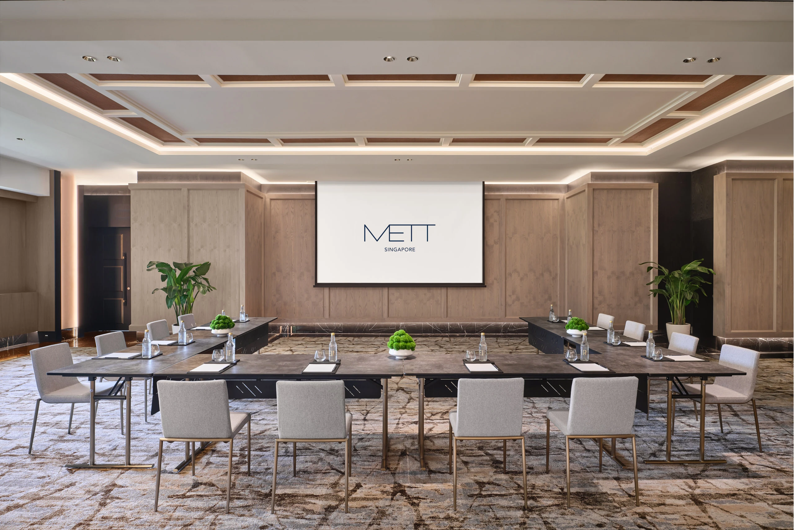 METT Singapore Junior Ballroom U-shape meeting setup with presentation screen, wood wall panelling, potted plants, and hospitality event seating