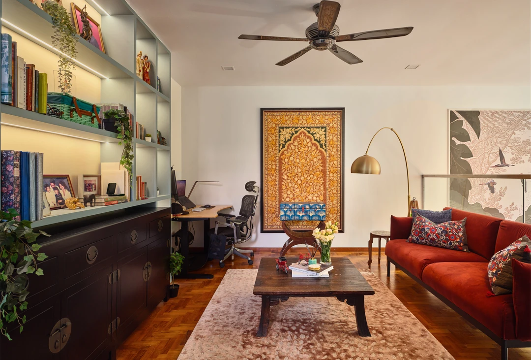 Serangoon Chuan Drive study lounge by Nidhi Jain with red leather sofa, built-in shelves, patterned rug and framed artwork