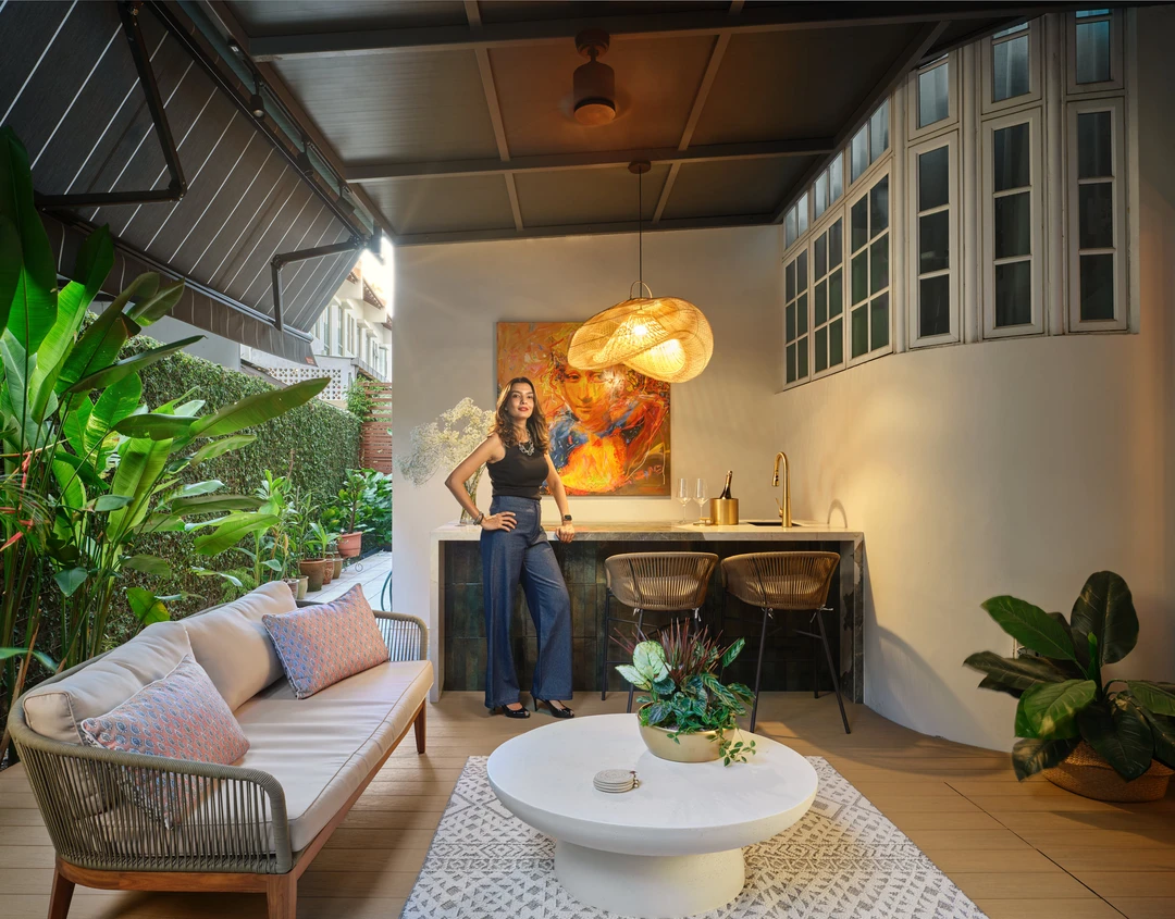 Interior designer Nidhi Jain on the covered terrace at Serangoon Chuan Drive with console bar, tropical plants and pendant light