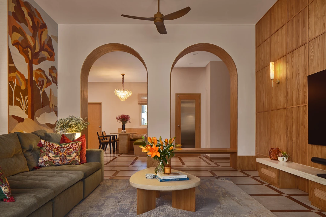 Bayshore living room by Nidhi Jain with arched openings, botanical mural, grey sofa and warm timber wall panels, crop detail