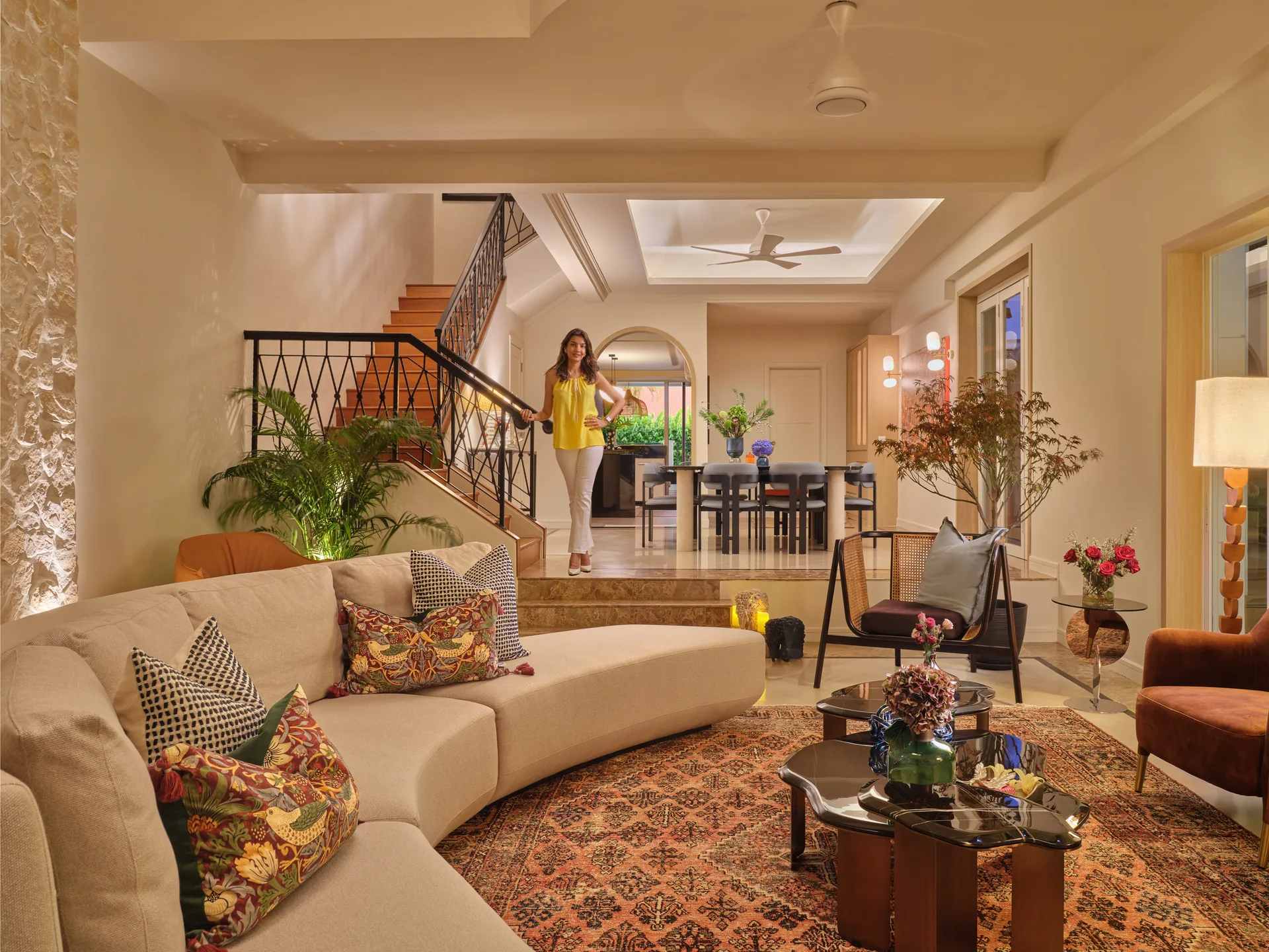 Living area with curved sectional, brass coffee table and arched alcoves