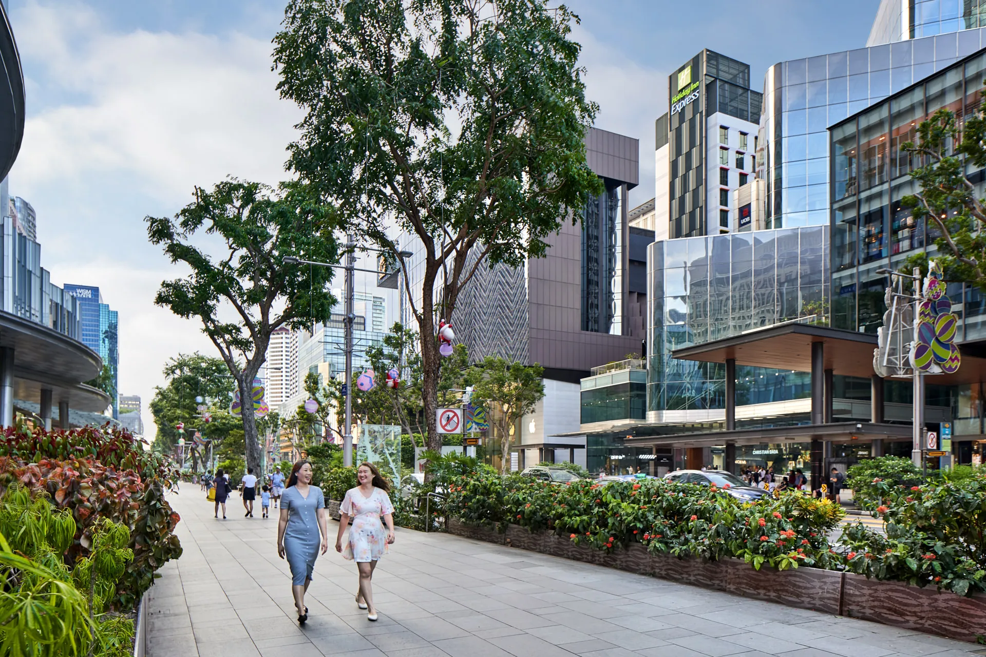 Two women walking along Orchard Road promenade with hotel signage — Holiday Inn Express Singapore lifestyle photography