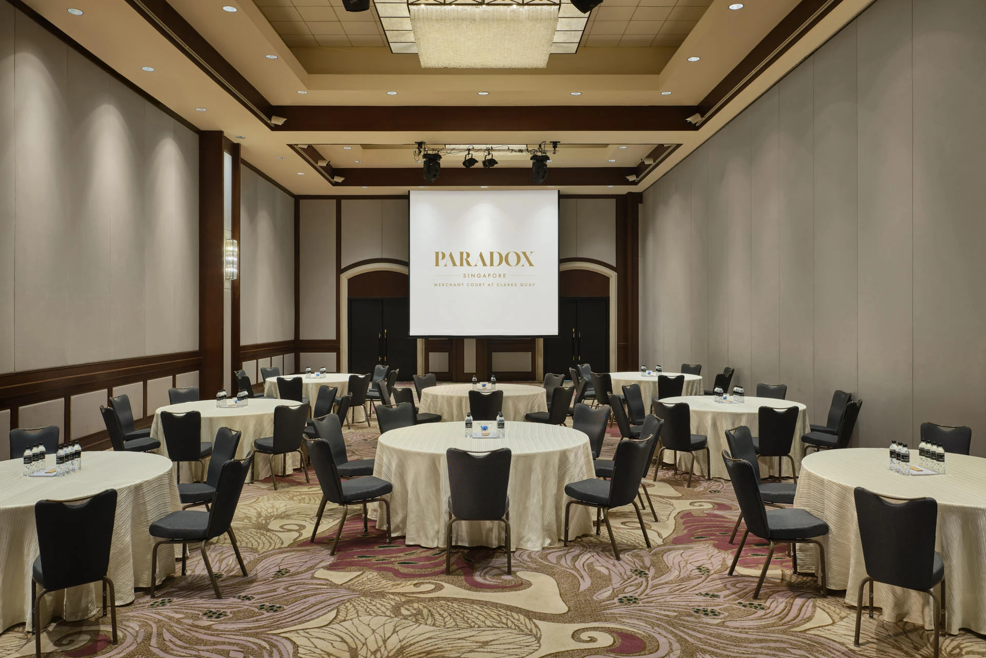 Paradox Singapore ballroom set for a cabaret-style corporate event with navy chairs and branded screen