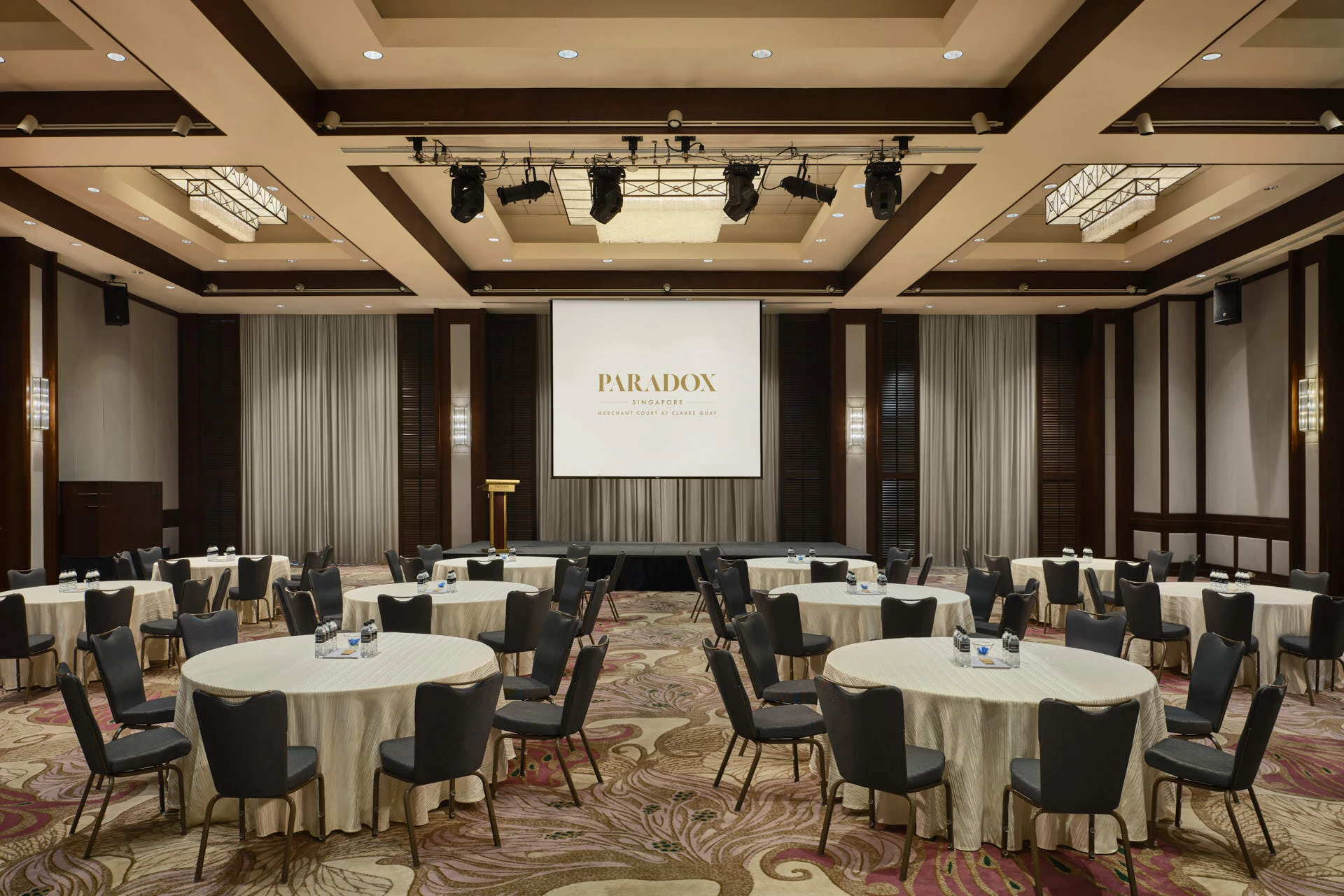 Paradox Singapore ballroom corporate seminar with round tables and branded projection screen