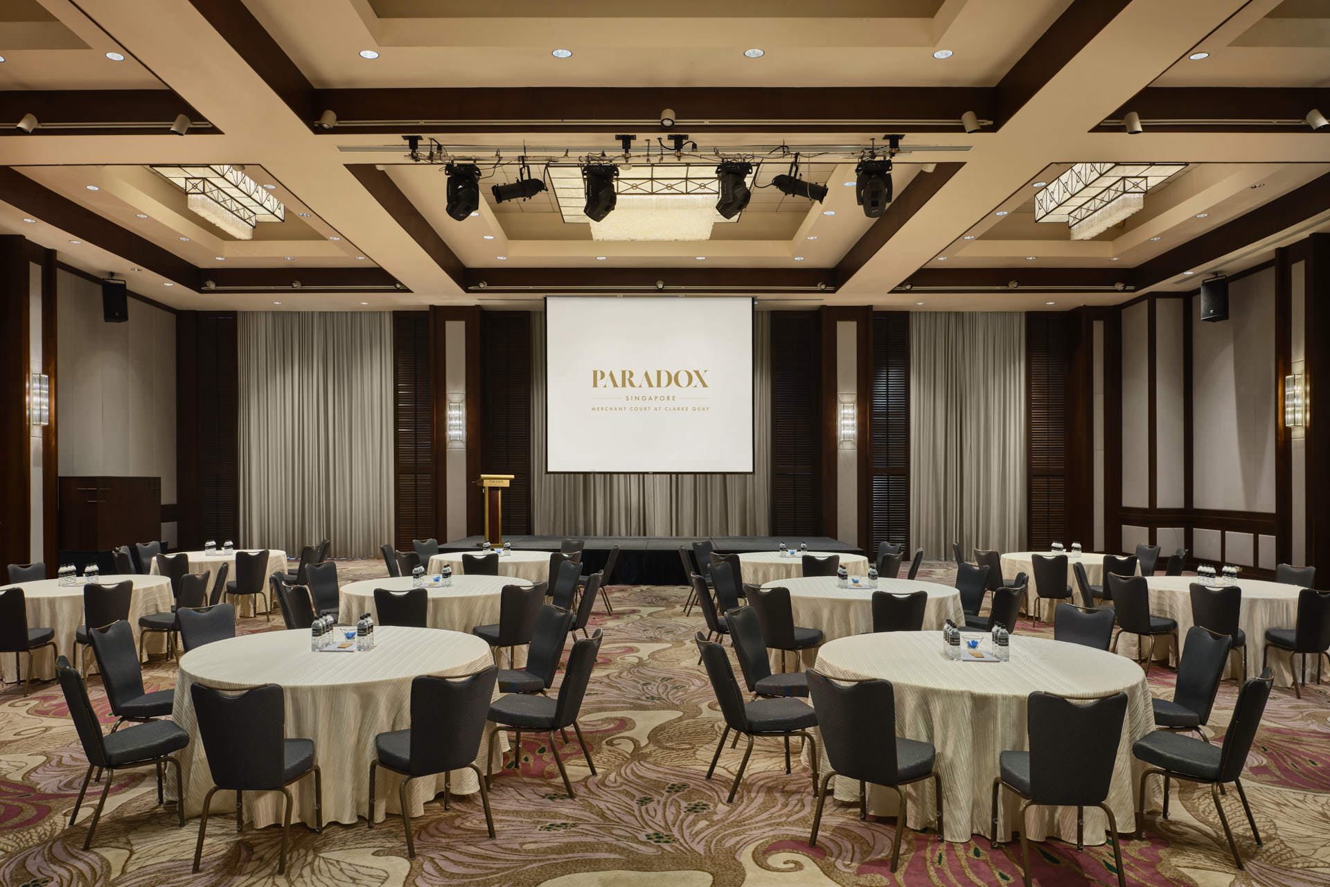 Paradox Singapore ballroom corporate seminar with round tables and branded projection screen