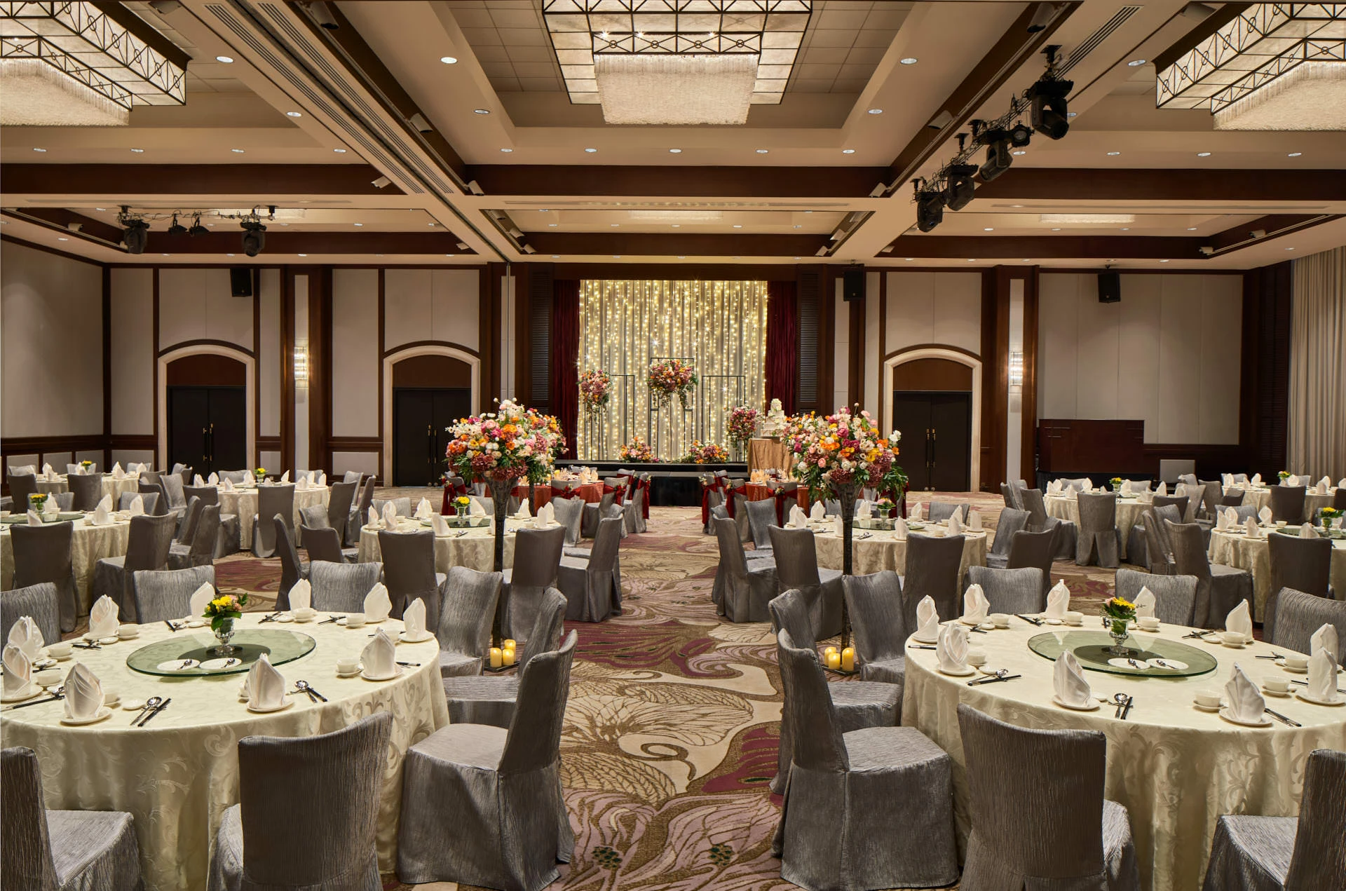 Paradox Singapore ballroom wedding banquet with ivory linens, floral aisle, and fairy-light backdrop