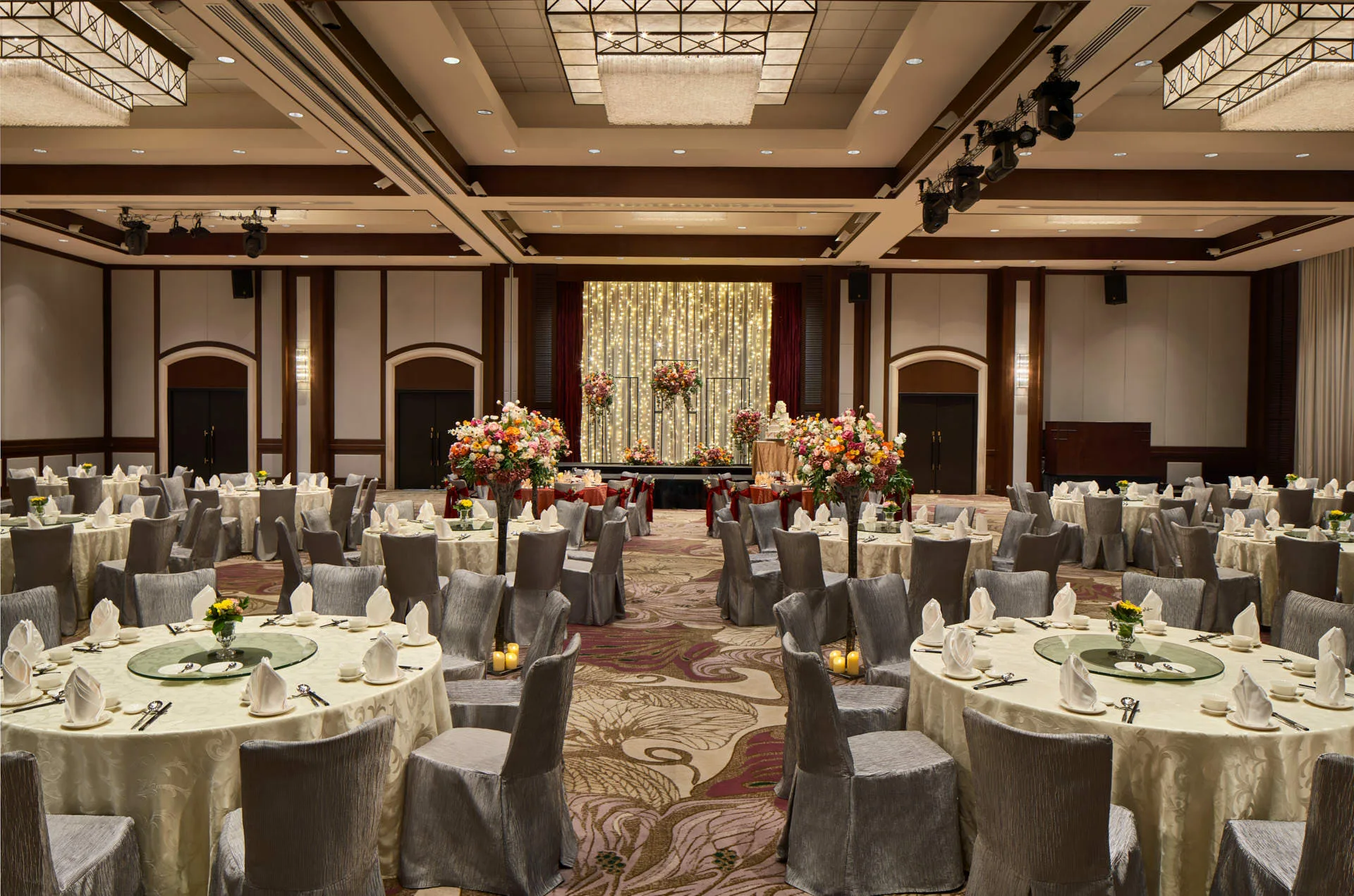 Paradox Singapore ballroom wedding banquet with ivory linens, floral aisle, and fairy-light backdrop