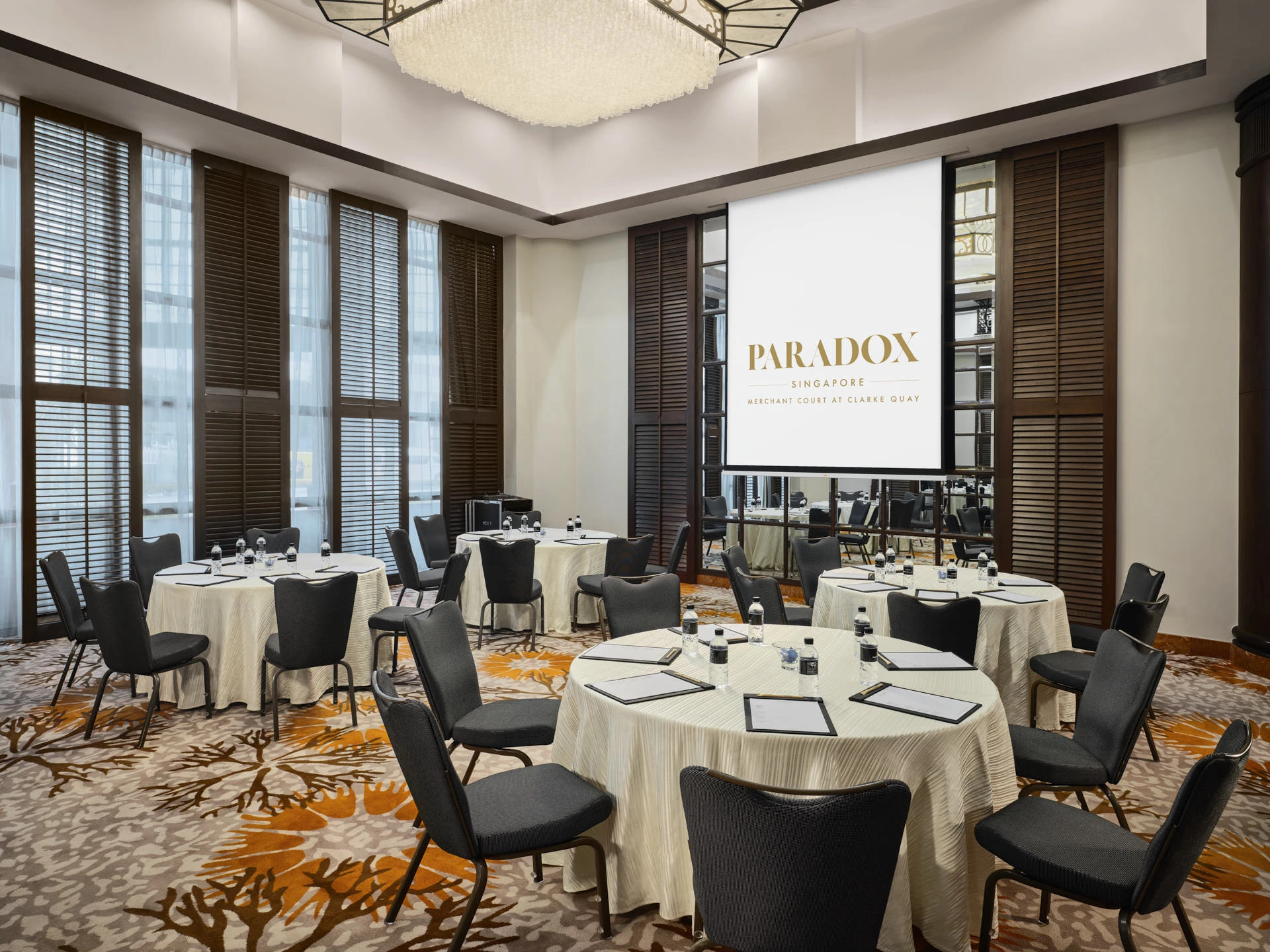 Paradox Singapore Inkwood Room cluster setup with louvred shutters, crystal chandelier, and coral carpet